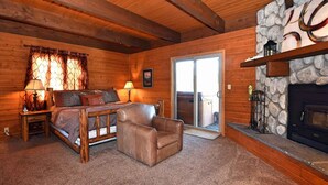 A cozy log cabin interior with a fireplace, a sofa, a chair, and a dining table. - Falling Leaf Retreat by Destination Big Bear : Lake Views! Hot Tub! Private! Fireplaces! Internet! Pool Table! (Big Bear Lake)