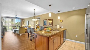 A modern kitchen with a central island, pendant lighting, and a view of the outdoors.