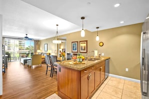 A modern kitchen with a central island, wooden cabinets, and pendant lighting.