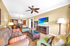 A modern living room with a sofa, armchairs, a coffee table, and a TV.