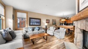 A spacious living room with a fireplace, a dining area, and a kitchen in the background. - High-end Finishes, 2 King Beds, Private Laundry, Overlooks Dercum Square (Keystone)