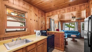 A wooden cabin interior with a kitchen, a dining area, and a living room. - Lakefront Cabin #5 The Bass (Presque Isle)