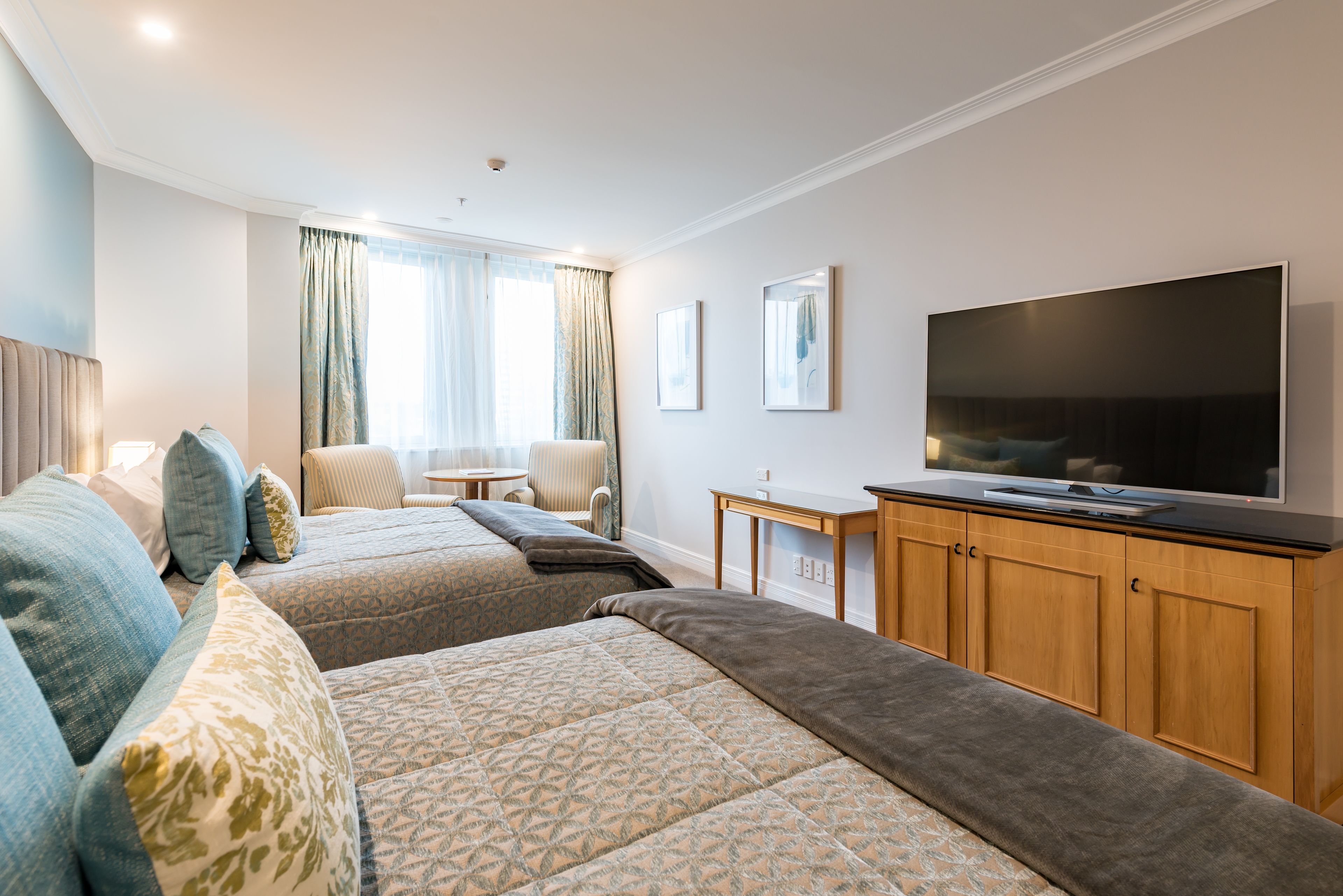 A hotel room with two beds, a TV, a desk, and a chair.