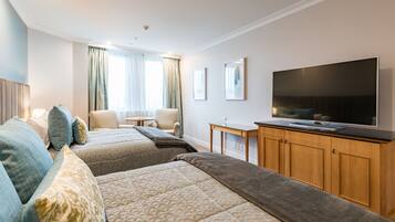 A hotel room with two beds, a TV, a desk, and a chair.