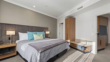 Een moderne slaapkamer met een bed, nachtkastjes, een ingebouwde bank, een garderobe en een televisie.