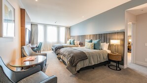 Hotelkamer met een groot bed, twee nachtkastjes, een stoel, een bureau en een raam met gordijnen.