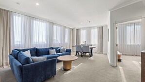 Een moderne woonkamer met een blauwe bank, een ronde salontafel en een eethoek met een tafel en stoelen.