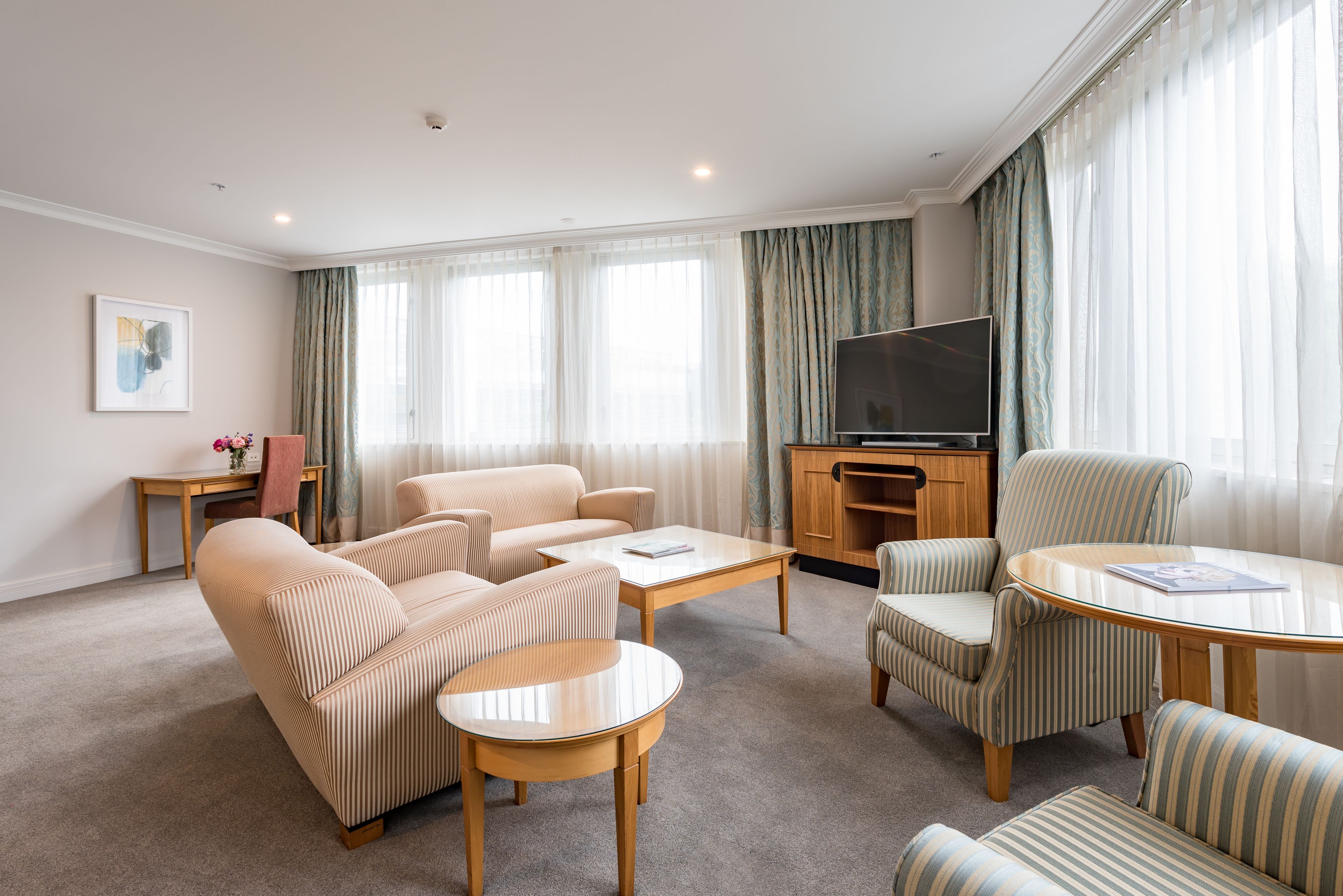 A modern living room with a sofa, armchairs, a coffee table, and a flat-screen TV.