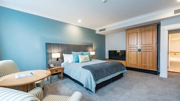 A hotel room with a bed, a desk, a chair, a wardrobe, and a television.