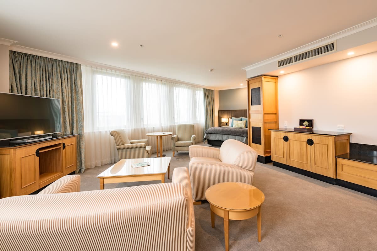 Een hotelkamer met een televisie, een bank, een bed, een bureau en een kast.