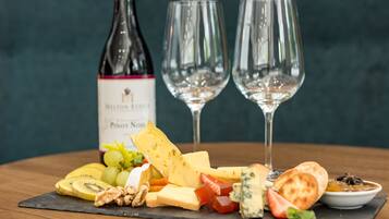A cheese board with various cheeses, fruits, nuts, and a bottle of wine on a slate board.