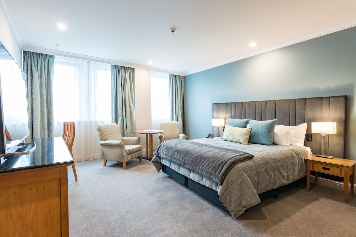 Een hotelkamer met een groot bed, twee nachtkastjes, een bureau en een stoel.