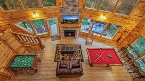A spacious lodge with a fireplace, pool table, foosball table, and a cozy seating area.