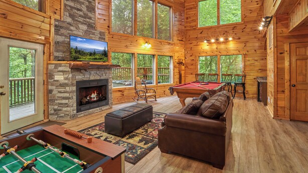 A spacious living room with a fireplace, a pool table, and a cozy seating area.