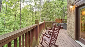A wooden deck with a rocking chair and a stone wall.
