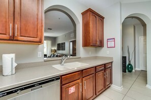 A kitchen with wooden cabinets, a dishwasher, and a double sink. - Resort Condo: 2BR w/ Balcony near Disney (Orlando)