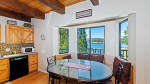A cozy kitchen with wooden cabinets, a microwave, and a dishwasher. There is a large window with a view of a lake and trees.