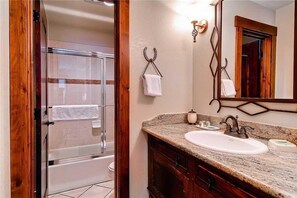 A bathroom with a glass shower enclosure, a sink with a marble countertop, wooden cabinets, and a large mirror. - Tr1106 Wonderfully Appointed, Walk to All Outdoor Activities- Winter Specials! (Steamboat Springs)