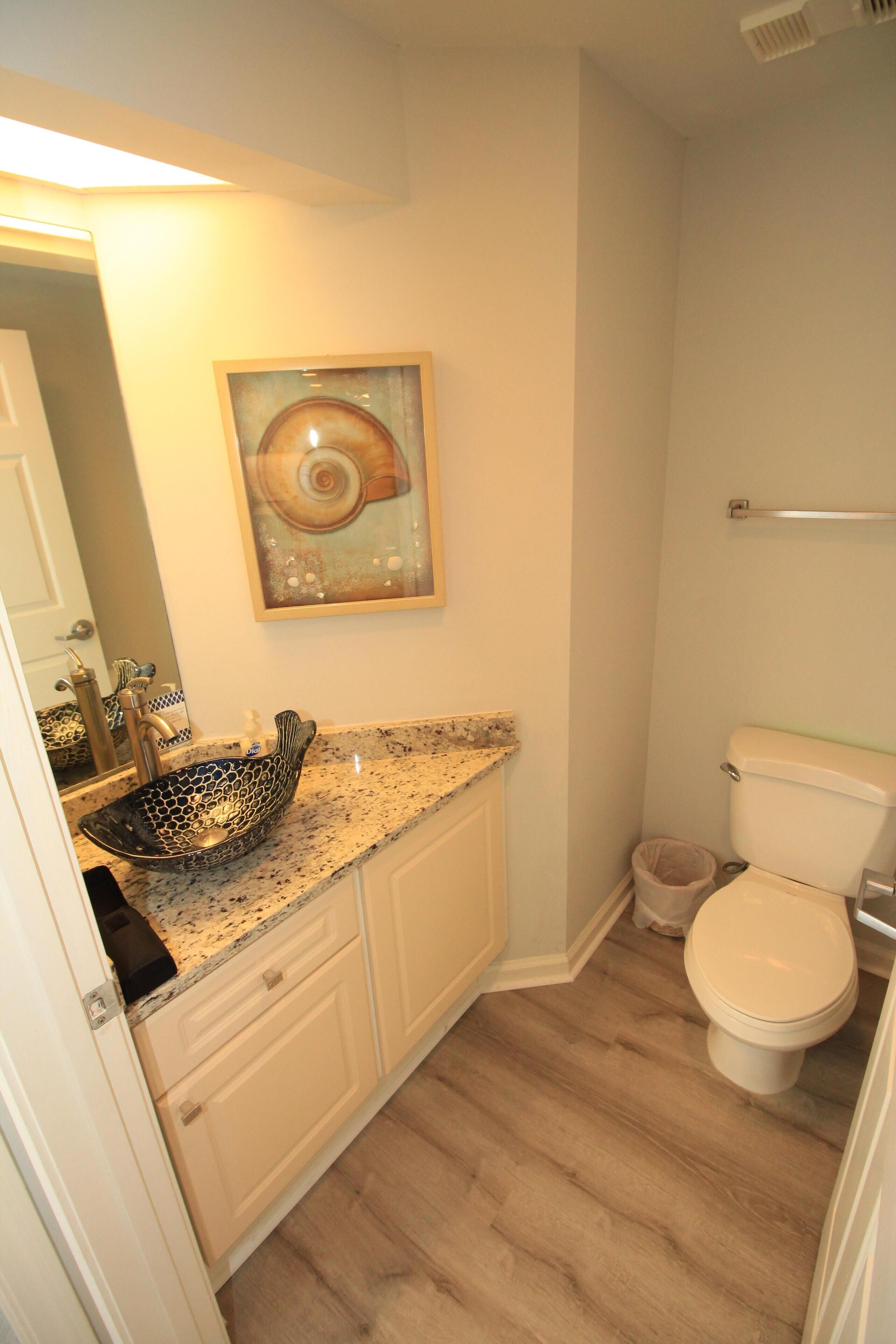 A bathroom with a vessel sink, toilet, and a painting on the wall.