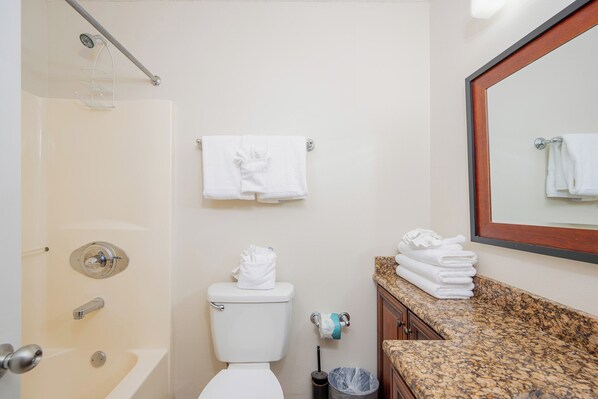 A bathroom with a shower, toilet, and sink with towels.