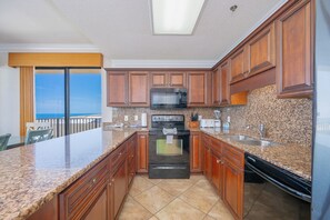 A kitchen with granite countertops, wooden cabinets, a microwave, stove, and dishwasher.