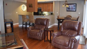 A spacious living area with leather armchairs, a glass coffee table, and a dining table with chairs.