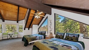 A bedroom with two beds, a ceiling fan, and large windows. - Movie Theater! Pool Table! HOT TUB! Mtn Views! Multiple Decks! (Big Bear Lake)