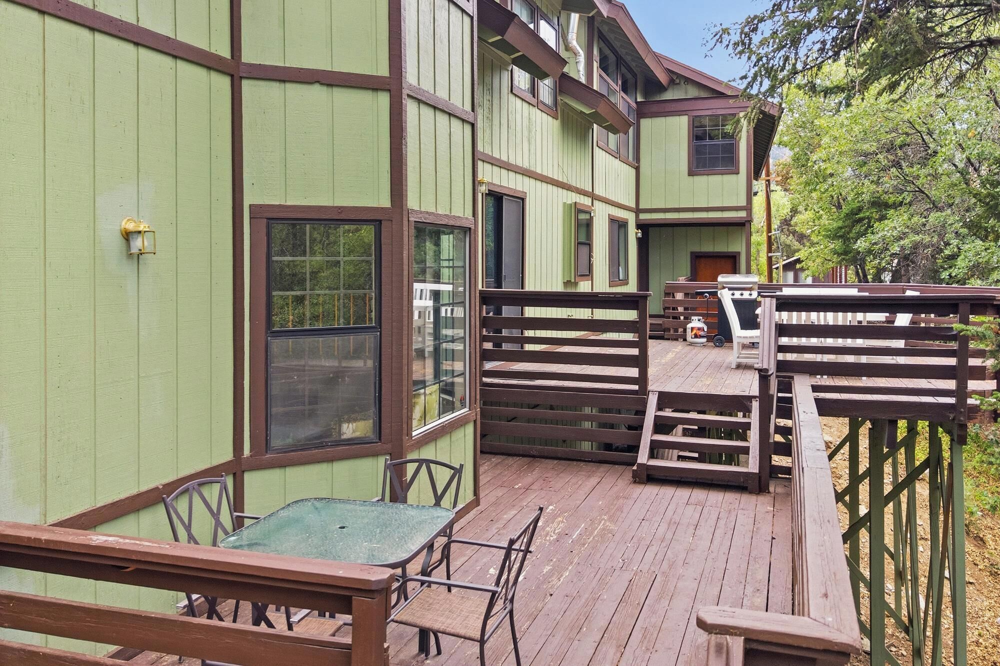 A wooden deck with a table and chairs, a wooden fence, and a building with multiple windows.