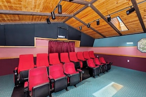Un teatro con butacas rojas, techo de madera y un escenario.