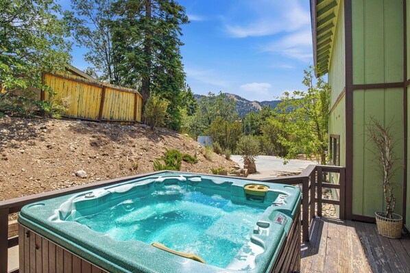 Un jacuzzi en una terraza de madera con montañas al fondo.