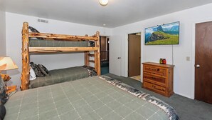 Una habitación con literas, un aparador, un televisor y una puerta.