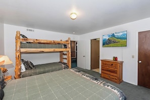 A room with a bunk bed, a dresser, a television, and a door. - Movie Theater! Pool Table! HOT TUB! Mtn Views! Multiple Decks! (Big Bear Lake)