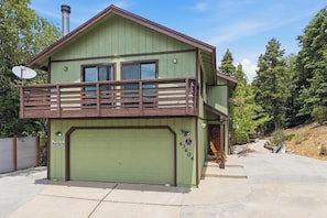 A two-story building with a green exterior, a balcony with wooden railings, and a garage door. - Movie Theater! Pool Table! HOT TUB! Mtn Views! Multiple Decks! (Big Bear Lake)