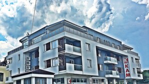 Un edificio de varios pisos con balcones, ventanas amplias y un letrero que dice "KAM".