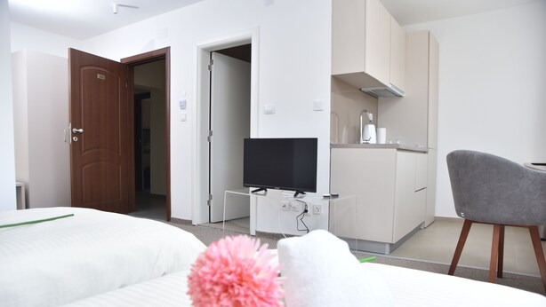 Habitación de hotel con dos camas, televisión, escritorio y una silla.