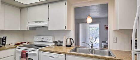 A modern kitchen with white cabinets, a stainless steel sink, and a built-in oven.