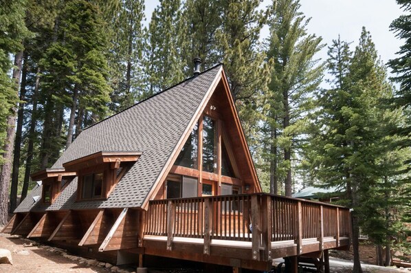 A wooden cabin with a sloped roof, multiple windows, and a deck. - Nicely updated Chambers cabin w/ pool, beach and tennis! (Homewood)