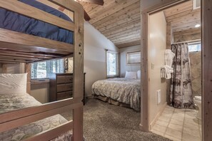 A bedroom with a bunk bed, a bedside table, a dresser, and a window. - Nicely updated Chambers cabin w/ pool, beach and tennis! (Homewood)