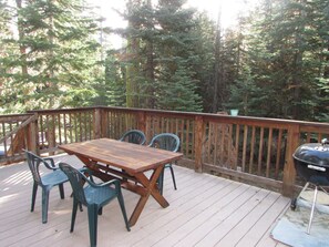 A wooden deck with a picnic table and chairs, surrounded by a wooden railing, and a barbecue grill. - Nicely updated Chambers cabin w/ pool, beach and tennis! (Homewood)