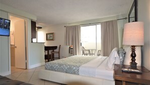 A hotel room with a bed, a desk, a chair, a lamp, and a TV. - Renovated Private Kuhio Village 708A Studio - 2 min Walk 2 the Beach! (Honolulu)