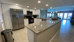 A modern kitchen with granite countertops, stainless steel appliances, and a large island. - "Breakers East 905"~Gulf Front 2 Bedroom/2 Bath Beach setup included (Destin)