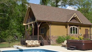 Een huis met een zwembad, een jacuzzi en tuinmeubilair.