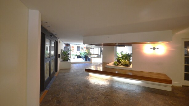 A hallway with stone flooring, a wooden bench, and potted plants.