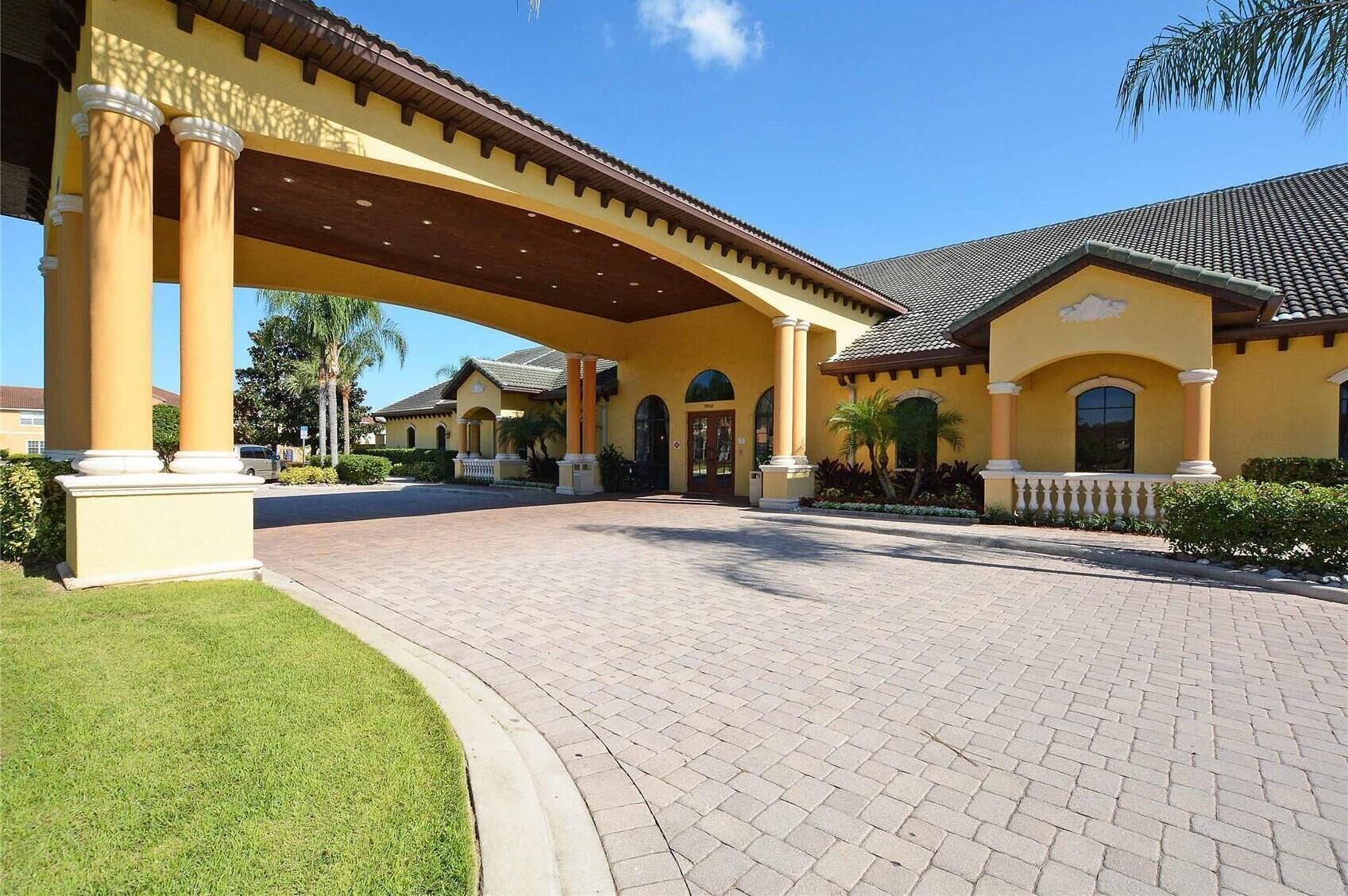 A yellow building with a covered entrance and a paved driveway.