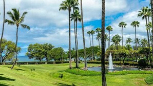 Een goed onderhouden golfbaan met een waterpartij en palmbomen.