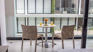 En matplats med två flätade stolar och ett runt bord, dekorerad med en vas med blommor och två glas apelsinjuice.