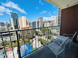 A balcony with a metal railing, a white metal chair, and a table.