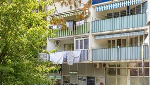 A multi-story building with balconies, some with clothes hanging. There are storefronts with signs, including one for a pharmacy. - Three BR ✦ Fully equipped large apartment✦ City center and beach proximity ✦ (Split)
