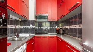 A modern kitchen with red cabinets, stainless steel appliances, and black and white tiled backsplash. - Three BR ✦ Fully equipped large apartment✦ City center and beach proximity ✦ (Split)