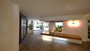 A hallway with a stone floor, a wooden bench, and potted plants. - KV1002 Waikiki 2463 Kuhio Ave Honolulu (Honolulu)
